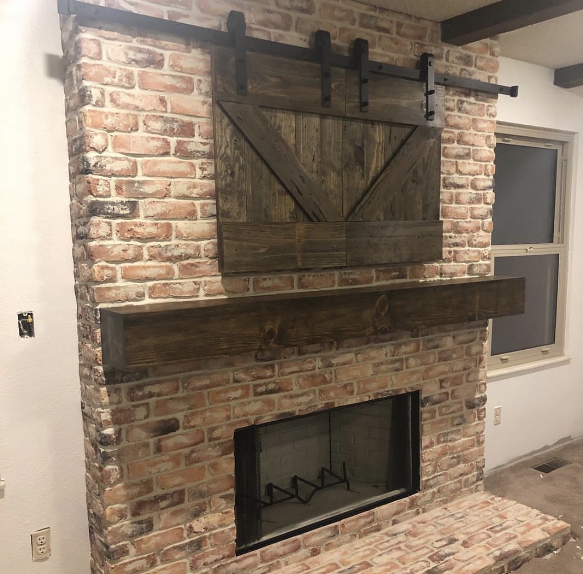 Brick fireplace & barn-door TV wall — Reclaimed brick, sliding hardware, hand-finished timber mantel